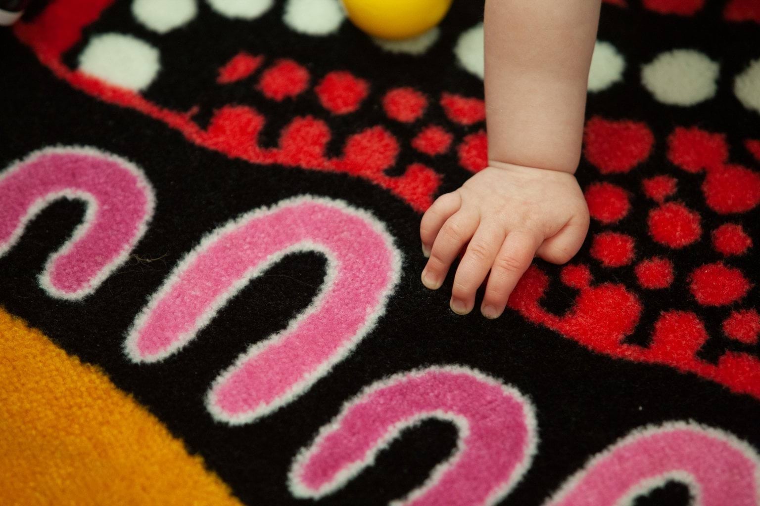 Child’s hand on woven Aboriginal dot painting rug at Early Learning Victoria Bani Walup (Murtoa).